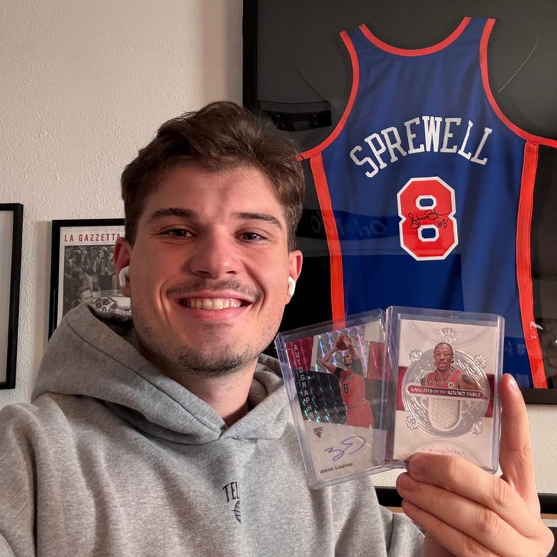 Daniel von @DunknDaniels hält zwei gegradete Sammelkarten vor einem Knicks-Trikot